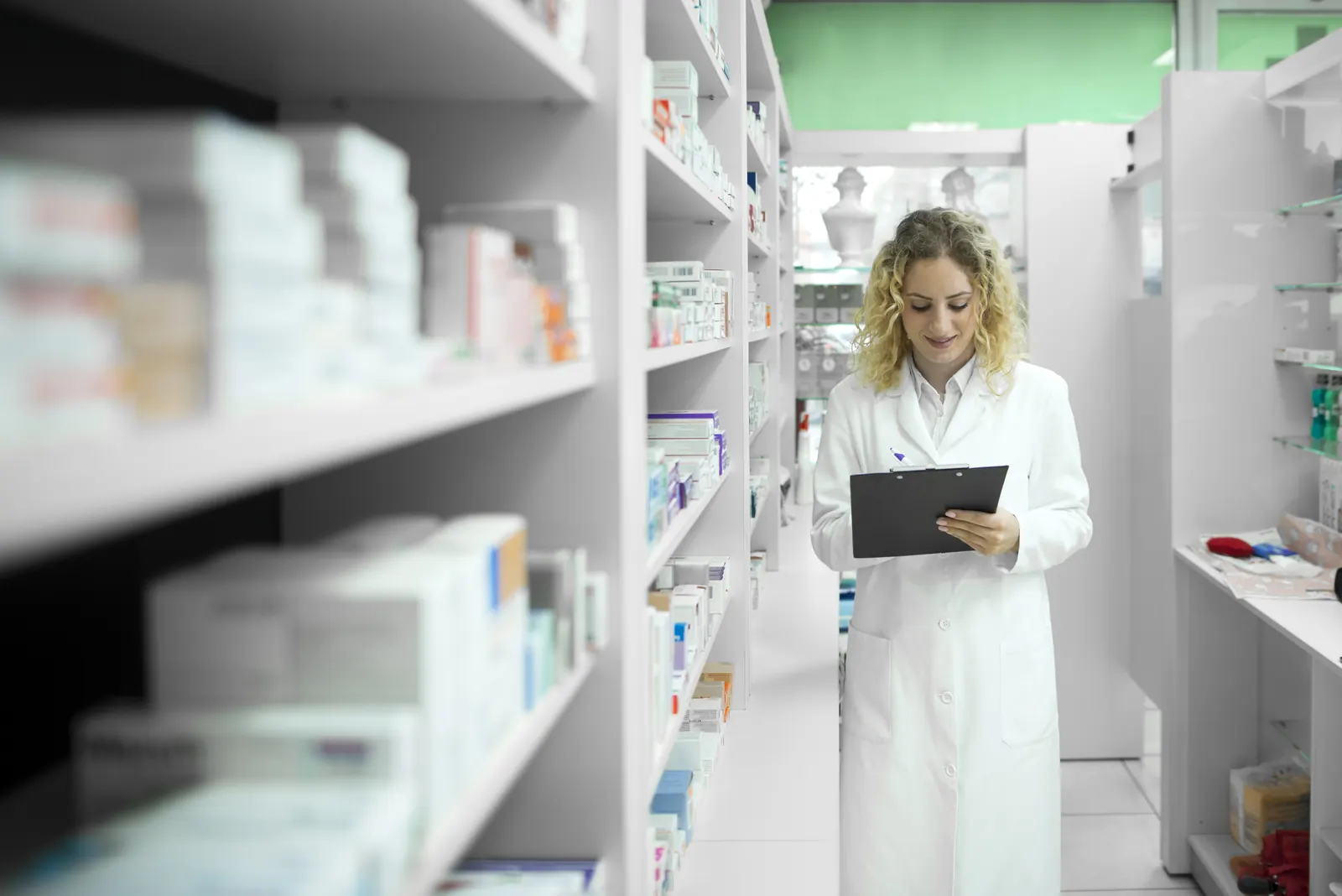 Farmacêutica conferindo estoque entre prateleiras